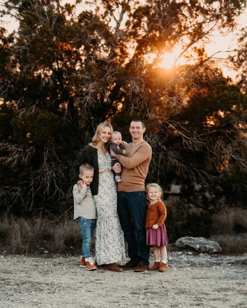 A family smiling at the camera at sunset.
