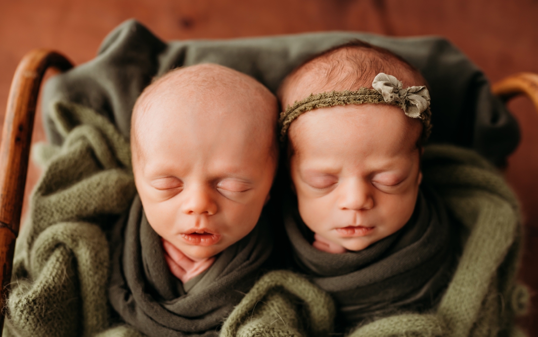 Newborn twins snuggled in swaddles.