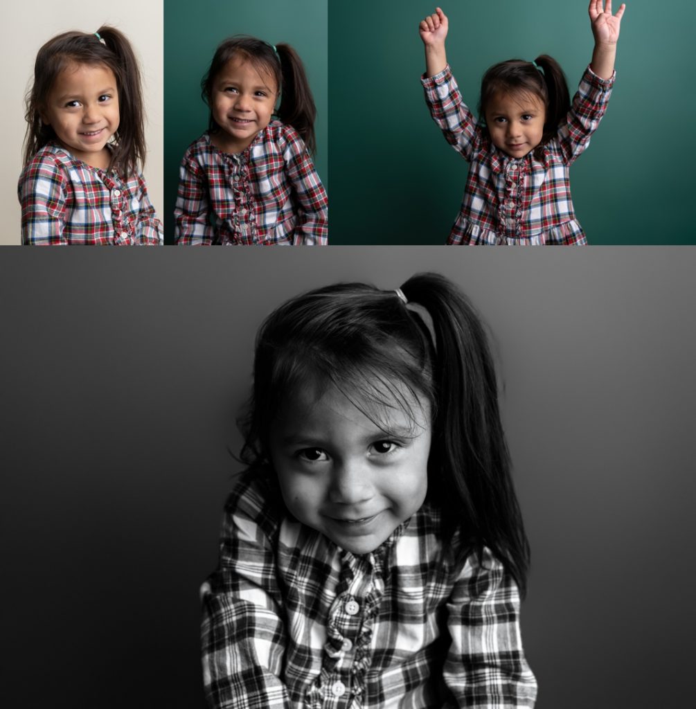 Little girl in a plaid dress sitting against a white backdrop and a green backdrop.