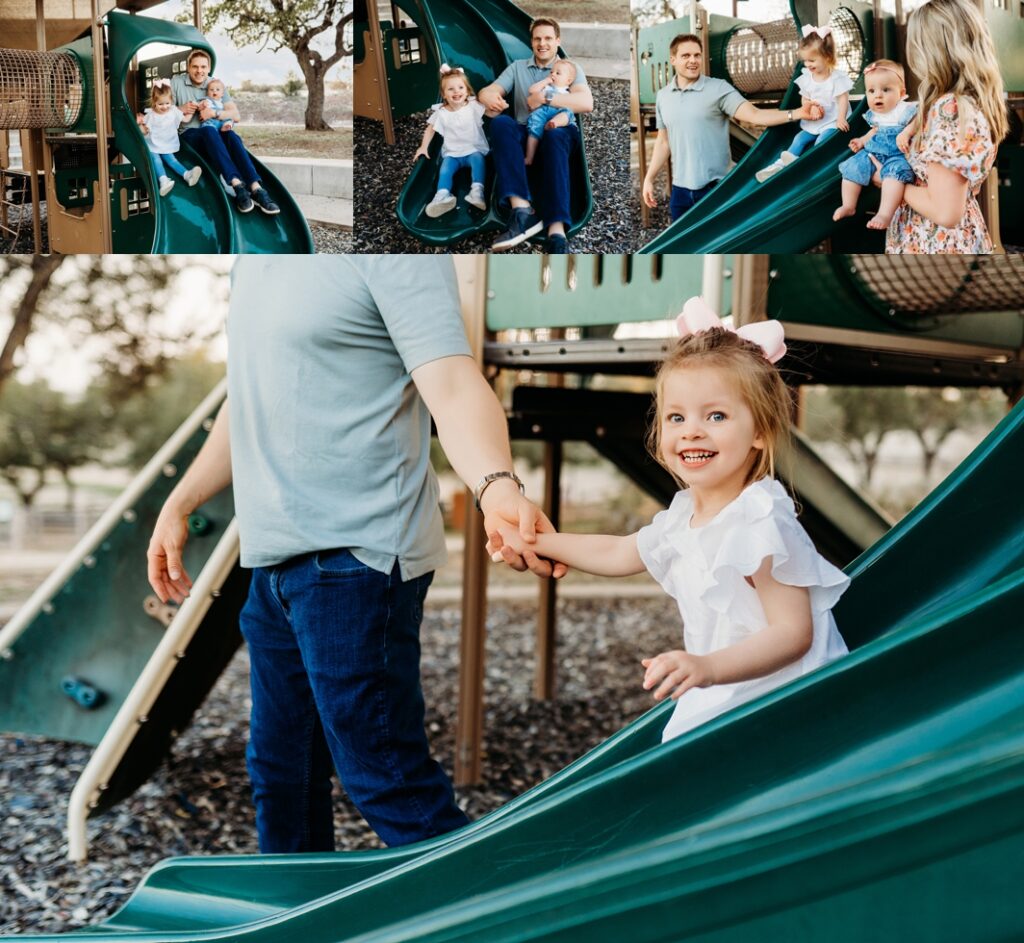 Dad holding little girl's hand as she slides down a slide. 